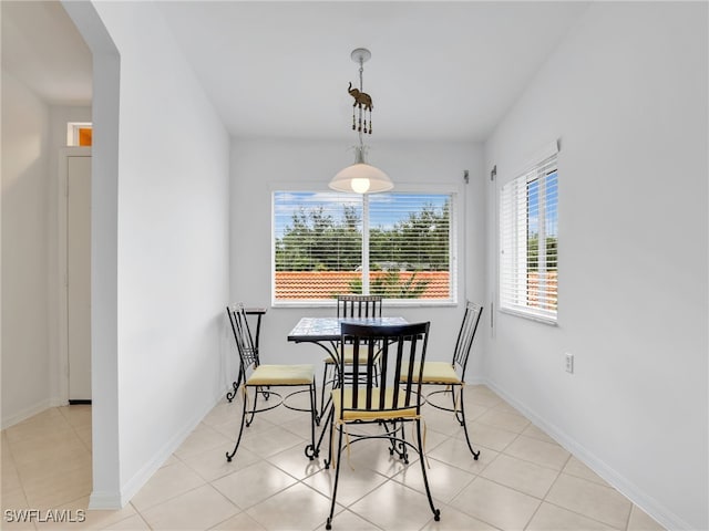 dining space with arched walkways, light tile patterned floors, and baseboards