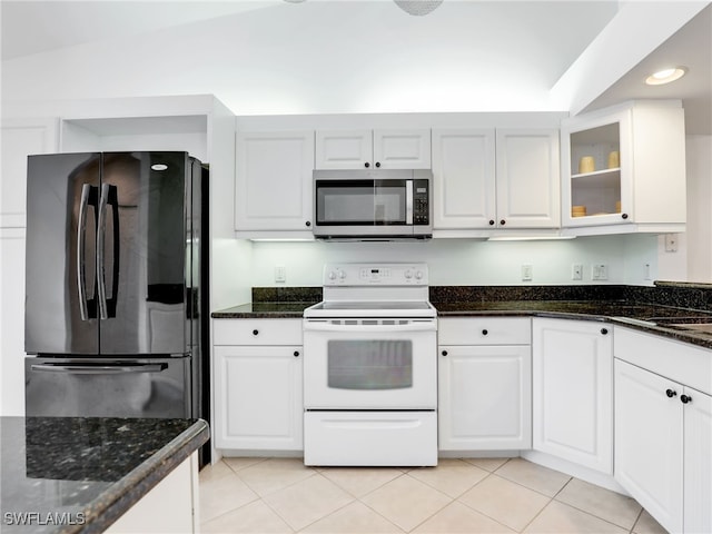 kitchen with white range with electric cooktop, stainless steel microwave, freestanding refrigerator, and white cabinetry