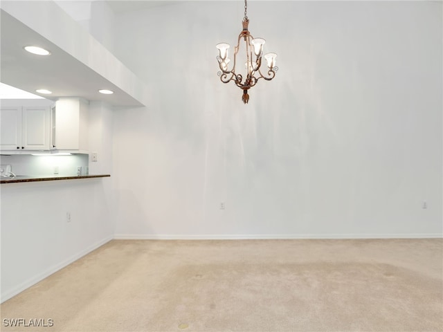 carpeted spare room featuring a notable chandelier