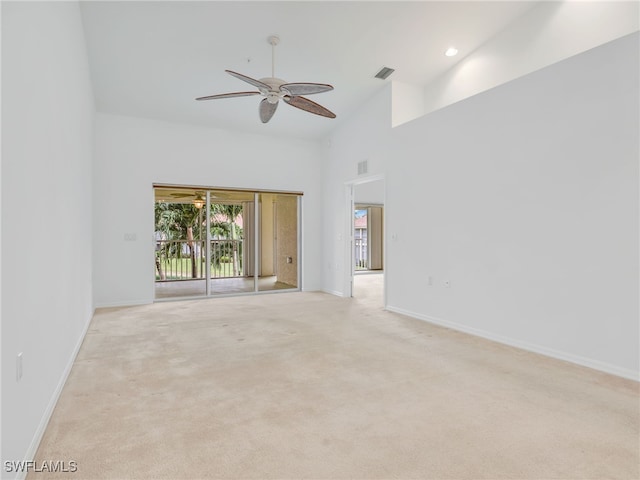 carpeted empty room with a towering ceiling and ceiling fan