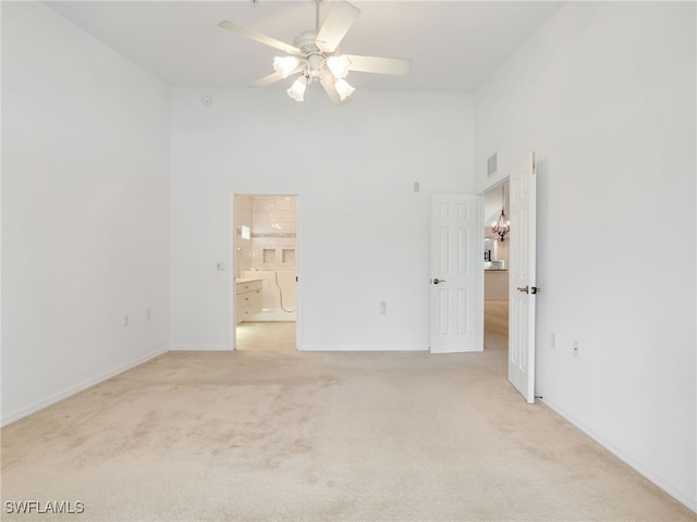 unfurnished bedroom featuring visible vents, light colored carpet, a high ceiling, ensuite bath, and baseboards