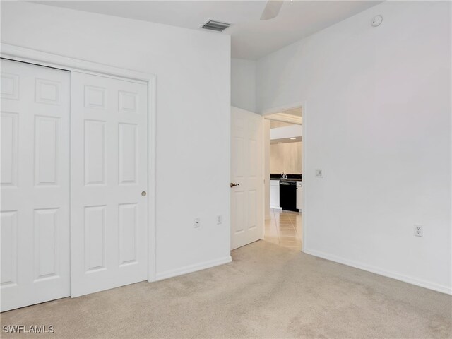 unfurnished bedroom with light colored carpet, a closet, and ceiling fan