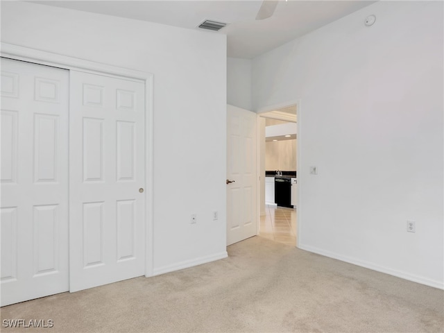 unfurnished bedroom with a closet, light colored carpet, visible vents, and baseboards