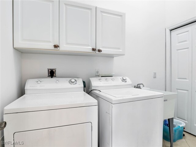 laundry area featuring cabinets, washing machine and dryer, and light tile patterned floors