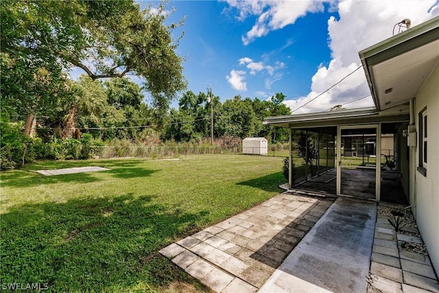 view of yard featuring a sunroom, a patio, and a storage shed