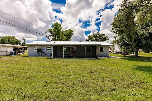 rear view of house featuring a carport, a sunroom, and a yard