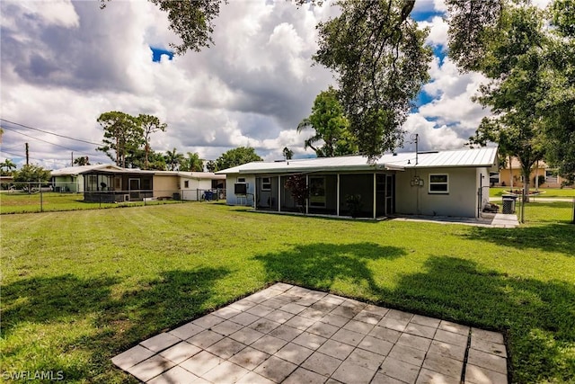 back of property with a yard, a patio, and a sunroom