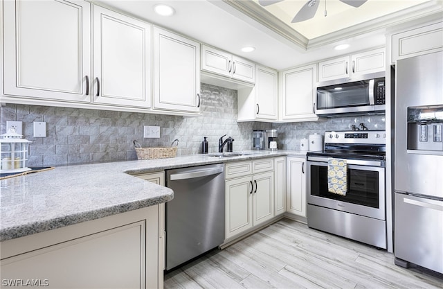 kitchen with light stone countertops, appliances with stainless steel finishes, sink, light hardwood / wood-style flooring, and white cabinetry