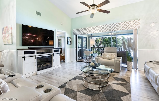 living room featuring ceiling fan, high vaulted ceiling, and light wood-type flooring