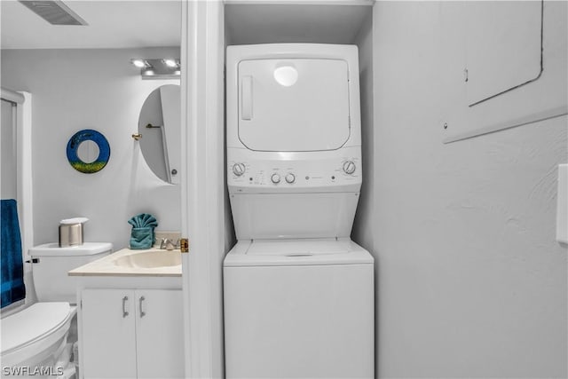 clothes washing area featuring stacked washer and dryer and sink