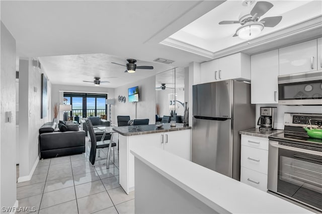 kitchen with ceiling fan, stainless steel appliances, light tile patterned floors, and white cabinets