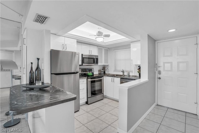 kitchen with kitchen peninsula, ceiling fan, stainless steel appliances, and white cabinets