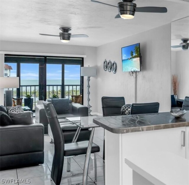 living room with a water view, ceiling fan, and light tile patterned floors