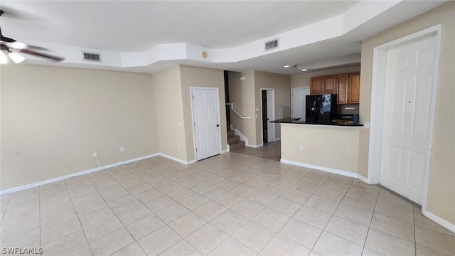 unfurnished living room featuring a raised ceiling, ceiling fan, and light tile patterned floors