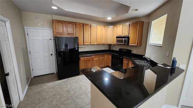 kitchen featuring kitchen peninsula, a tray ceiling, sink, black appliances, and light tile patterned flooring