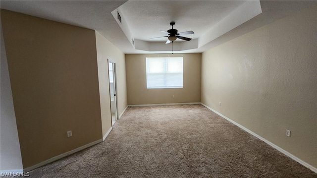 carpeted empty room with a textured ceiling, a tray ceiling, and ceiling fan