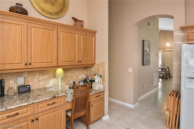 kitchen with white refrigerator with ice dispenser, tasteful backsplash, light stone countertops, and light tile patterned floors