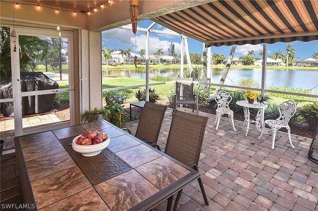 sunroom featuring a water view