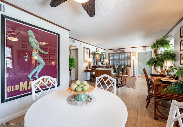 dining space featuring crown molding, ceiling fan, light hardwood / wood-style floors, and a textured ceiling