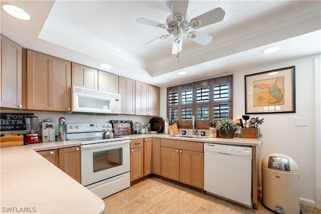 kitchen with ceiling fan, sink, white appliances, a tray ceiling, and light wood-type flooring