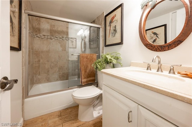 full bathroom with hardwood / wood-style floors, vanity, toilet, and enclosed tub / shower combo