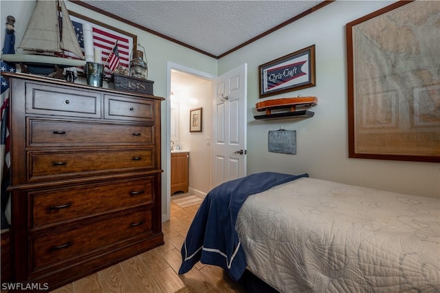 bedroom featuring light wood-type flooring, a textured ceiling, and ensuite bath