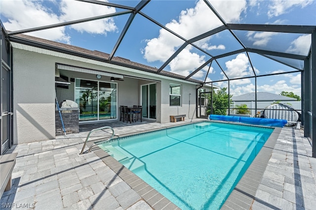 view of pool with a lanai, ceiling fan, a grill, exterior kitchen, and a patio