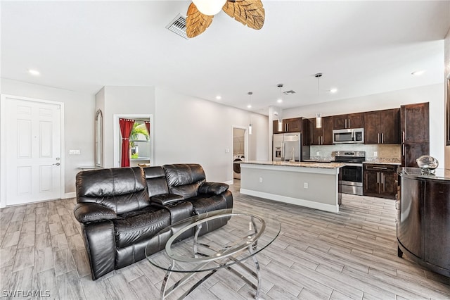 living room with washer / clothes dryer, light hardwood / wood-style flooring, and ceiling fan