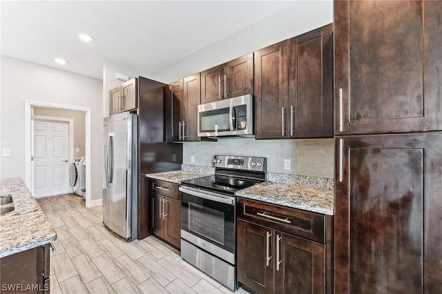 kitchen featuring light stone countertops, washing machine and dryer, appliances with stainless steel finishes, and dark brown cabinetry