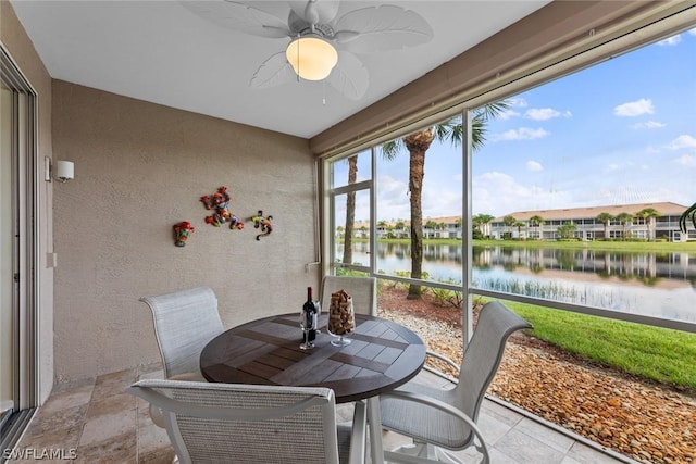 sunroom / solarium featuring ceiling fan and a water view