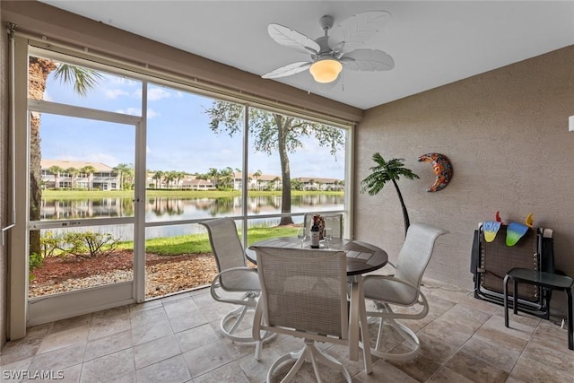 sunroom / solarium with ceiling fan and a water view