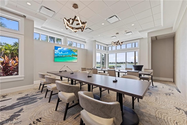 office space with carpet, a towering ceiling, and a notable chandelier