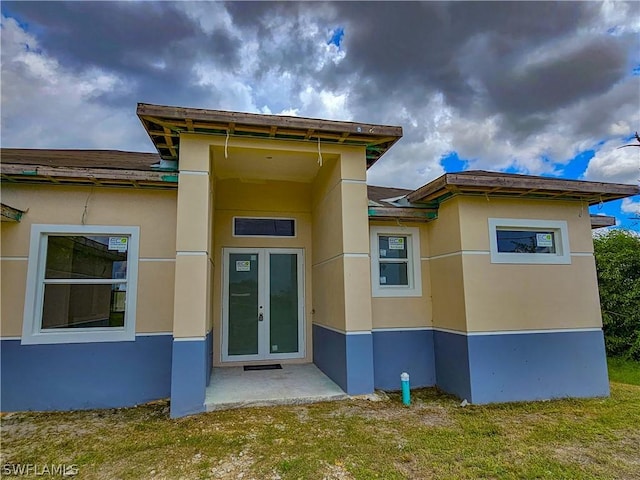 4111 22nd St SW, Lehigh Acres, FL 33976 - back of property with french doors, stucco siding, and a lawn