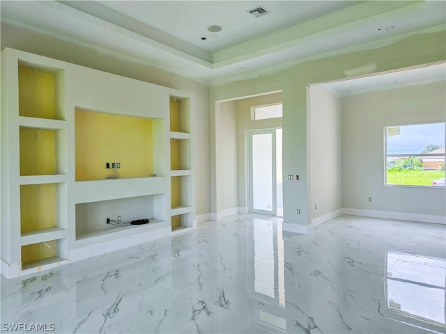 unfurnished living room with built in features, tile patterned flooring, and a tray ceiling