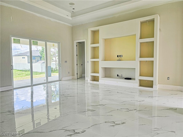 tiled empty room with built in shelves, a tray ceiling, and a towering ceiling