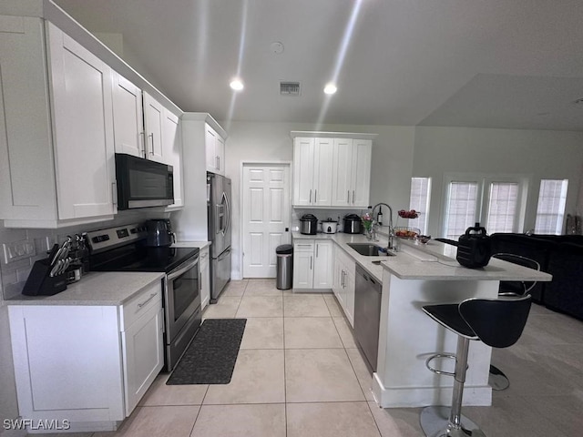 kitchen with white cabinets, kitchen peninsula, and appliances with stainless steel finishes