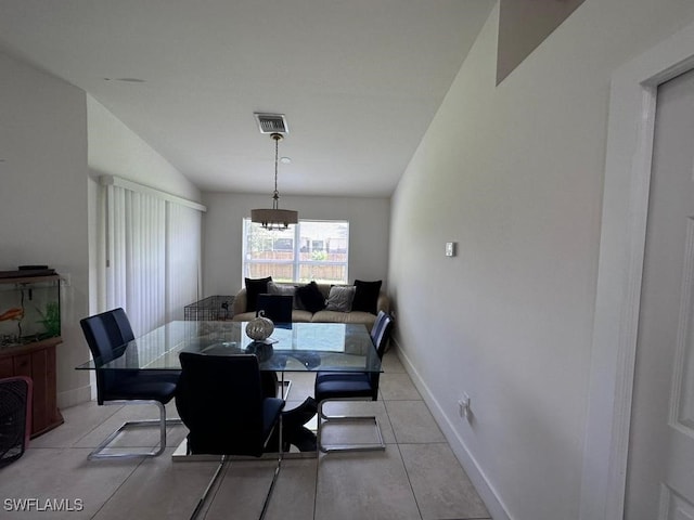 tiled dining room featuring vaulted ceiling