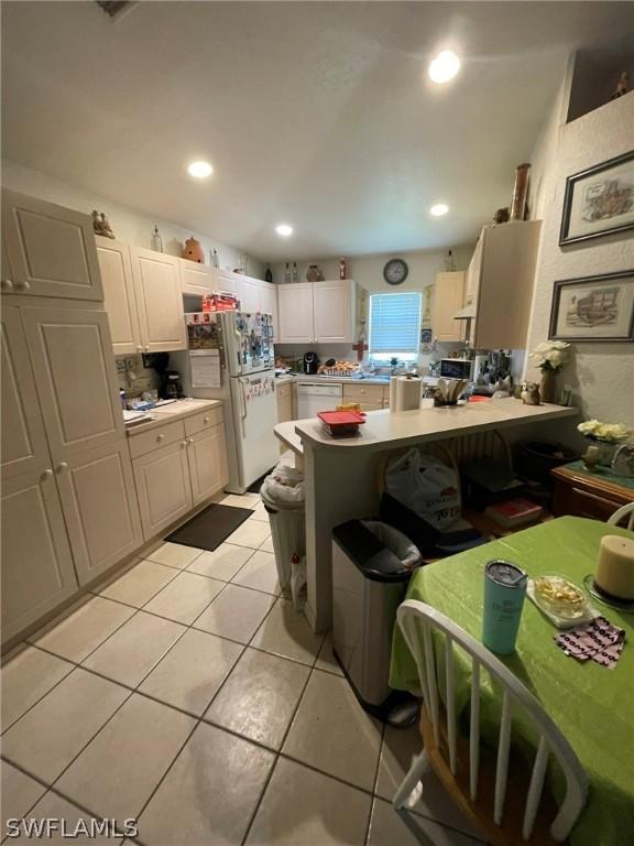 kitchen with kitchen peninsula, white fridge, a breakfast bar area, and light tile patterned flooring