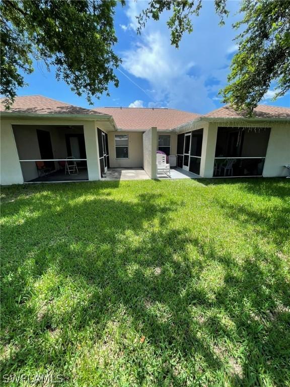 back of property with a patio, a lawn, and a sunroom