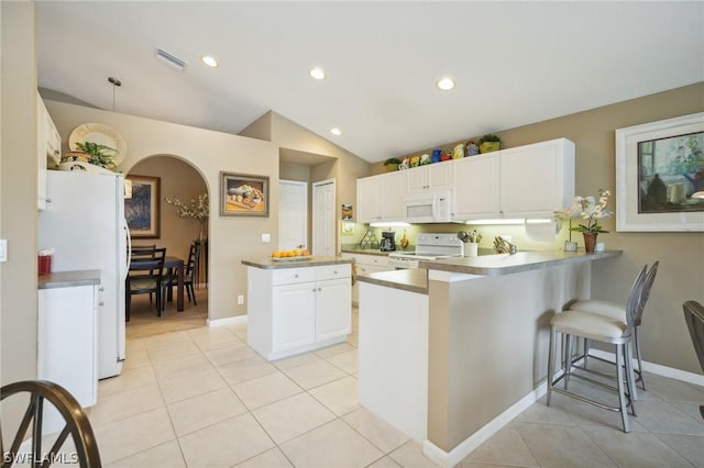 kitchen featuring white cabinetry, white appliances, vaulted ceiling, and kitchen peninsula