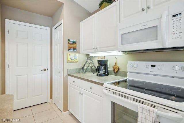 kitchen featuring light tile patterned flooring, white cabinets, and white appliances