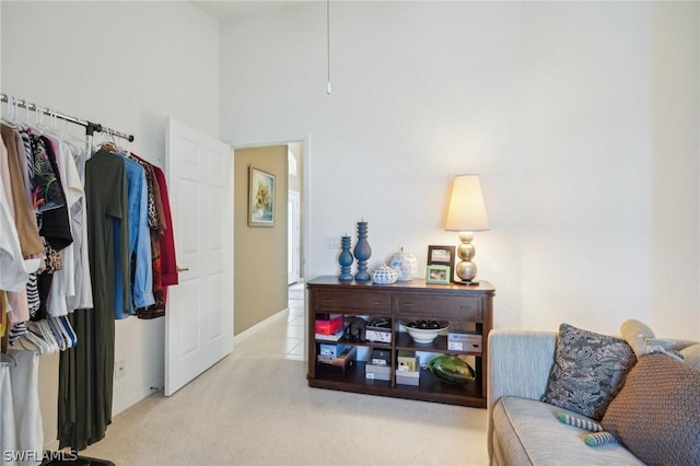 sitting room featuring a towering ceiling and light colored carpet