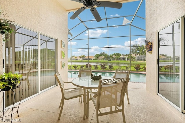 sunroom featuring a water view and ceiling fan