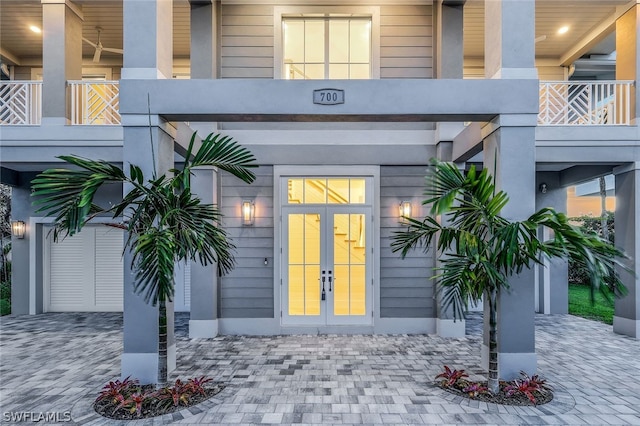 property entrance with a garage, a balcony, and french doors