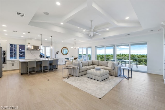 living area with light wood finished floors, plenty of natural light, coffered ceiling, and visible vents