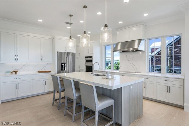 kitchen featuring crown molding, backsplash, stainless steel appliances, light hardwood / wood-style floors, and wall chimney exhaust hood