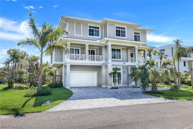 coastal home featuring a front yard, decorative driveway, and an attached garage