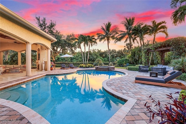 pool at dusk with an in ground hot tub, a patio area, ceiling fan, and an outdoor hangout area