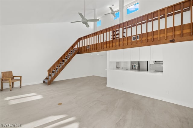 unfurnished living room featuring ceiling fan and a towering ceiling