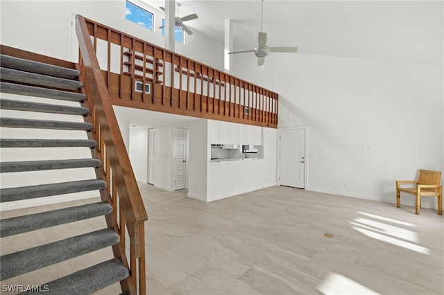 staircase with ceiling fan and a towering ceiling